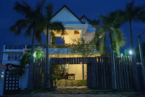 a house with a fence and palm trees at night at Boravin House in Siem Reap