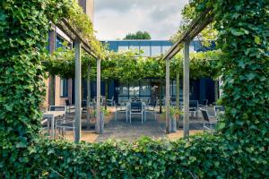 un patio con mesas, sillas y plantas en Mercure Hotel Zwolle, en Zwolle