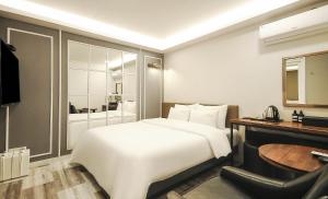 a hotel room with a large white bed and a desk at Hotel Louis in Busan