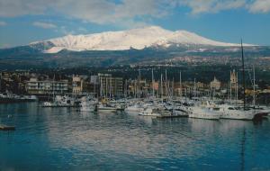 a bunch of boats docked in a harbor with a snow covered mountain at Scariceddu in Riposto