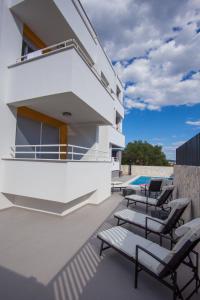 a white house with chairs and a swimming pool at Residences Bellavista 3 in Novalja