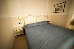 a bedroom with a bed with a blue comforter at Hotel Gran Duca in Livorno