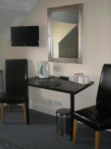 a table with two chairs and a mirror in a room at Elmswood Guest House in South Shields