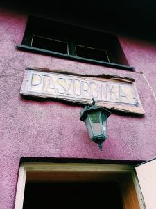 um sinal na lateral de um edifício cor-de-rosa com uma lâmpada em Ptaszorowka em Szczyrk