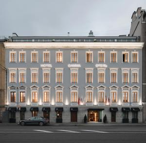 um grande edifício branco com um carro estacionado em frente em Boutique Hotel The Gamma em São Petersburgo