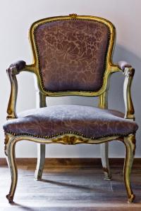 an ornate chair with a leather seat in a room at Nonna Giulina in Castagnole Lanze
