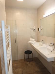 łazienka z umywalką, lustrem i stołkiem w obiekcie Hotel Hohe Tauern w mieście Matrei in Osttirol