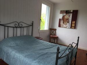 a bedroom with a bed with a blue bedspread and a window at Gites les Grandes Gouttes in Le Syndicat