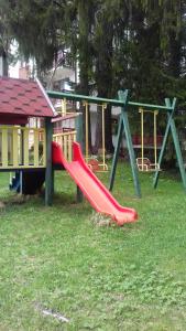 un parque infantil con un tobogán rojo en el césped en TES Rila Park Apartments, en Borovets