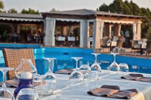 a table with wine glasses and napkins next to a pool at Residence Stella Di Gallura in Porto Rotondo