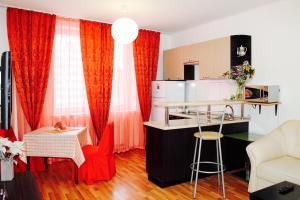 a kitchen and a living room with red curtains at Aristokrat Apartments in Yekaterinburg