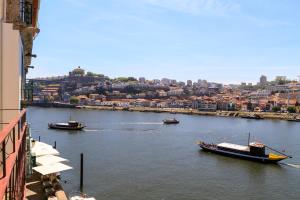 Tres barcos en un río con una ciudad en el fondo en Oporto Home - River Front, en Oporto
