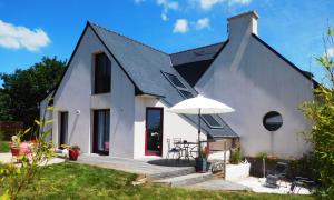 a white house with a black roof and an umbrella at Sud Bretagne Concarneau Tregunc Pont-avenTyruzall in Trégunc