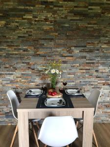 a dining room table with white chairs and a brick wall at ApartamentyPodZakopanem.PL in Murzasichle