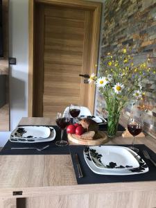 a table with two plates and glasses of wine at ApartamentyPodZakopanem.PL in Murzasichle