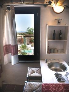 La salle de bains est pourvue d'un lavabo et d'une fenêtre avec vue. dans l'établissement Antico Casale del Poggio, à Capoterra