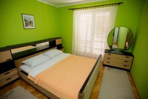 a green bedroom with a bed and a mirror at Apartment City Heart in Trebinje