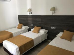 two beds in a hotel room with brown and white at Hotel Restaurante Santa Cruz in Santa Cruz de Mudela