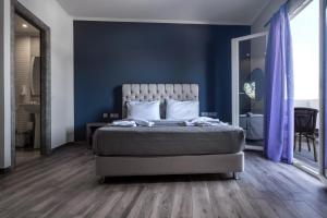 1 dormitorio con 1 cama con paredes azules y suelo de madera en Zante Calinica Hotel en Tsilivi