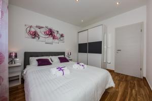 Un dormitorio con una gran cama blanca con almohadas moradas. en Lavender & Mint, en Kaštela