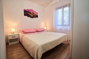 Schlafzimmer mit einem Bett mit rosa Kissen und einem Fenster in der Unterkunft Villa Nada in Neum