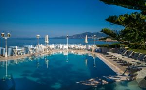 a swimming pool with chairs and the ocean in the background at Hotel Le Maquis in Porticcio