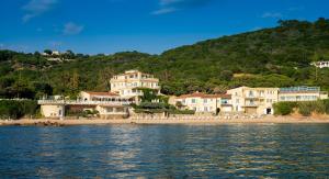 a group of houses on a beach next to the water at Hotel Le Maquis in Porticcio