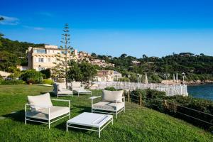 a group of chairs and a table in the grass at Hotel Le Maquis in Porticcio