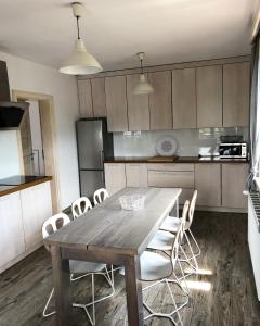 a kitchen with a wooden table and white chairs at Carlina House in Szczawnica