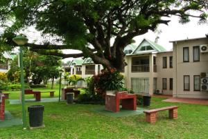 a park with benches and a tree in front of a building at 62 The Bridge Holiday Resort in St Lucia