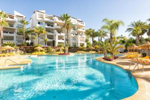 a swimming pool at a resort with palm trees at Sea & mountain view penthouse in Estepona