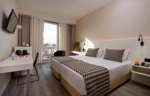 a hotel room with a bed and a desk at Occidental Faro in Faro +37 photos
