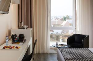 a hotel room with a bed and a chair and a window at Occidental Faro in Faro