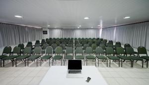 una habitación llena de sillas verdes y un ordenador portátil en una mesa en Iracema Travel, en Fortaleza