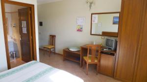 1 dormitorio con 1 cama y escritorio con TV en Hotel da Paolino, en Trinità dʼAgultu