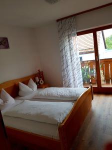 a bedroom with two beds and a large window at Gästehaus Schrötter in Lam