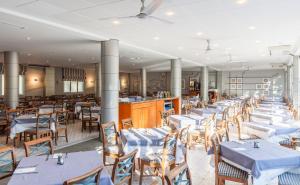 une salle à manger avec des tables et des chaises blanches dans l'établissement BLUESEA Es Bolero, à Cala d´Or