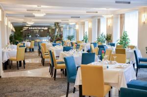 a dining room with white tables and blue chairs at Hotel Afrodita -Valenii De Munte in Vălenii de Munte