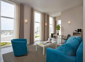 a living room with a blue couch and chairs at Occidental Faro in Faro