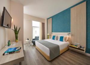 a hotel room with a large bed and a desk at Occidental Faro in Faro
