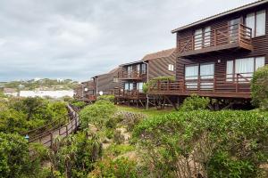 a row of cottages with balconies and a stairway leading up to at First Group Kowie River Chalets in Port Alfred