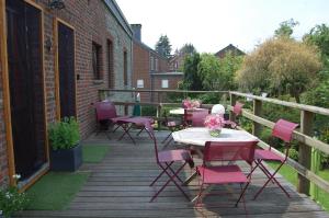 eine Terrasse mit rosa Stühlen und Tischen auf einer Terrasse in der Unterkunft Appartement Fleurs des champs - Esc'Appart in Rochefort
