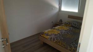 1 Schlafzimmer mit einem Bett mit Blumenbettdecke und einem Fenster in der Unterkunft Apartmani Jadranka in Vodice
