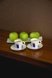 two cups of coffee on a wooden table with apples at City5 ROOMS & SUITES by LSA in Skopje