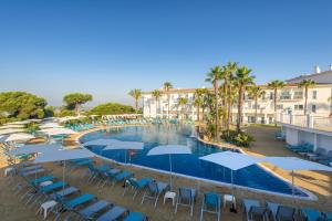 a swimming pool with blue chairs and umbrellas at Garden Playanatural - Adults Only in El Rompido +37 photos