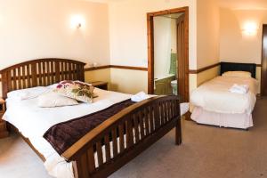 a bedroom with two beds and a mirror at Fernhill Bed and Breakfast in Rochdale