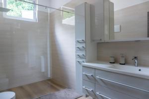 a white bathroom with a sink and a shower at Nature View House with Sauna in Tolmin