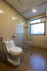 a bathroom with a toilet and a glass shower at Hotel Phoenix Koregaon Park in Pune