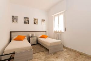 two beds with orange pillows in a white room at Ad Astra Suite in Rome