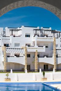 un edificio blanco con una piscina frente a él en Alcudia Smir Apartment, en Fnidek